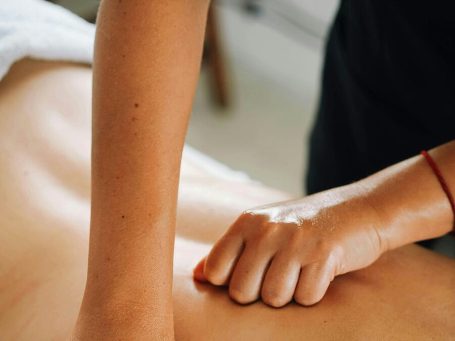 Terapeuta a pressionar com o antebraço os músculos das costas de um cliente